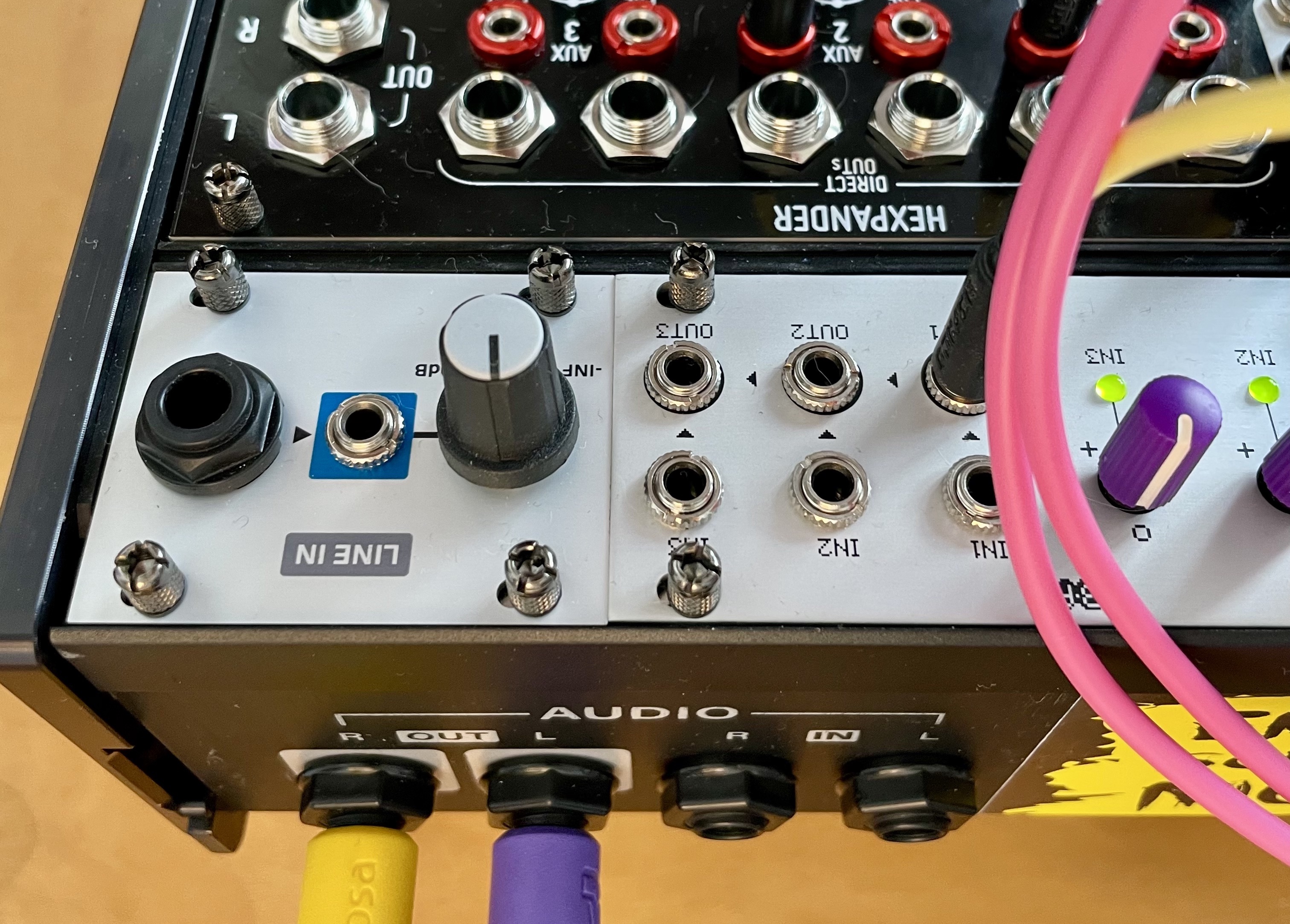 The rear of an Intellijel case with cables plugged into the audio out jacks. Mounted in the case is a Befaco HEXMIX (HEXPANDER) and hair of my cats.